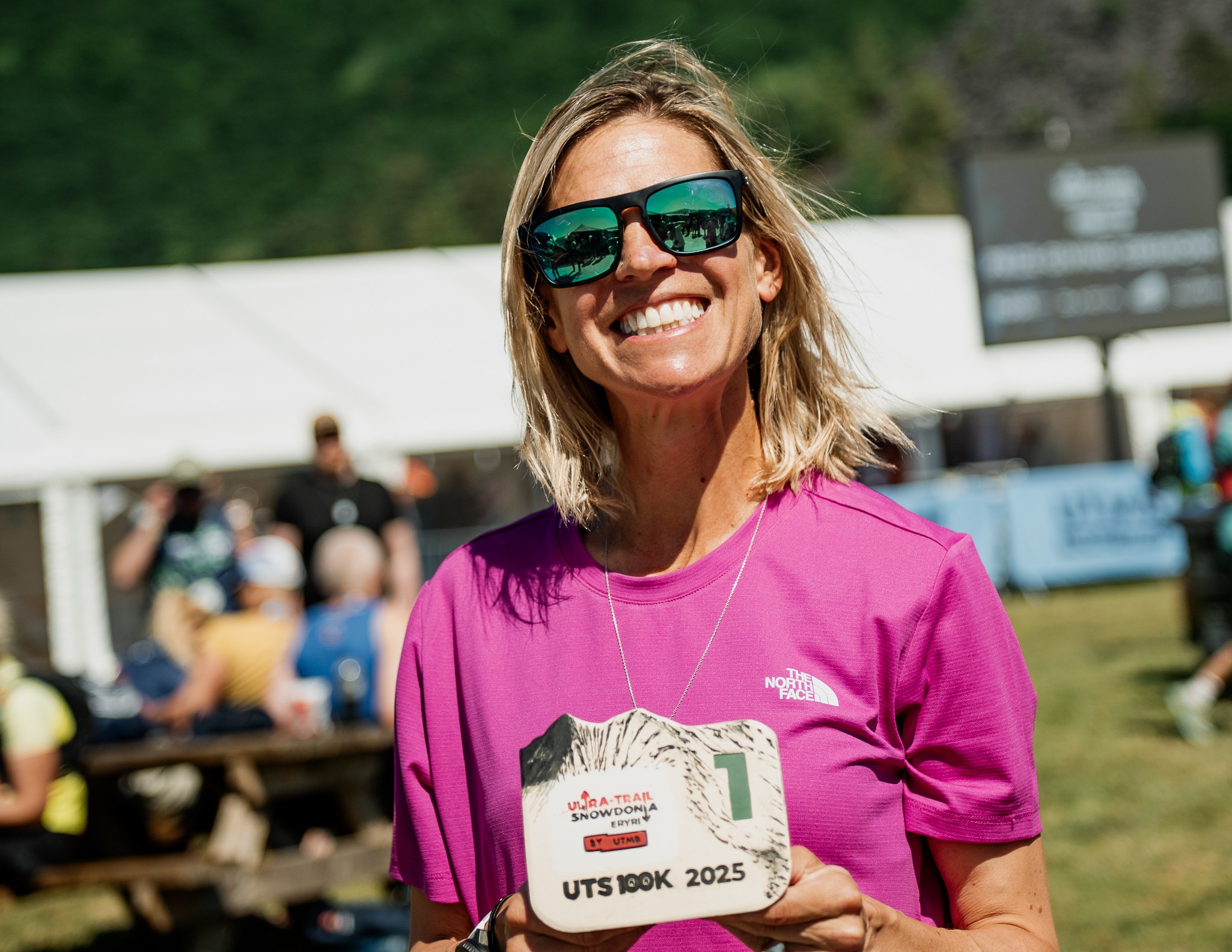 Stephanie Case holding her Ultra-Trail Snowdonia 100k 2025 finisher's medal.