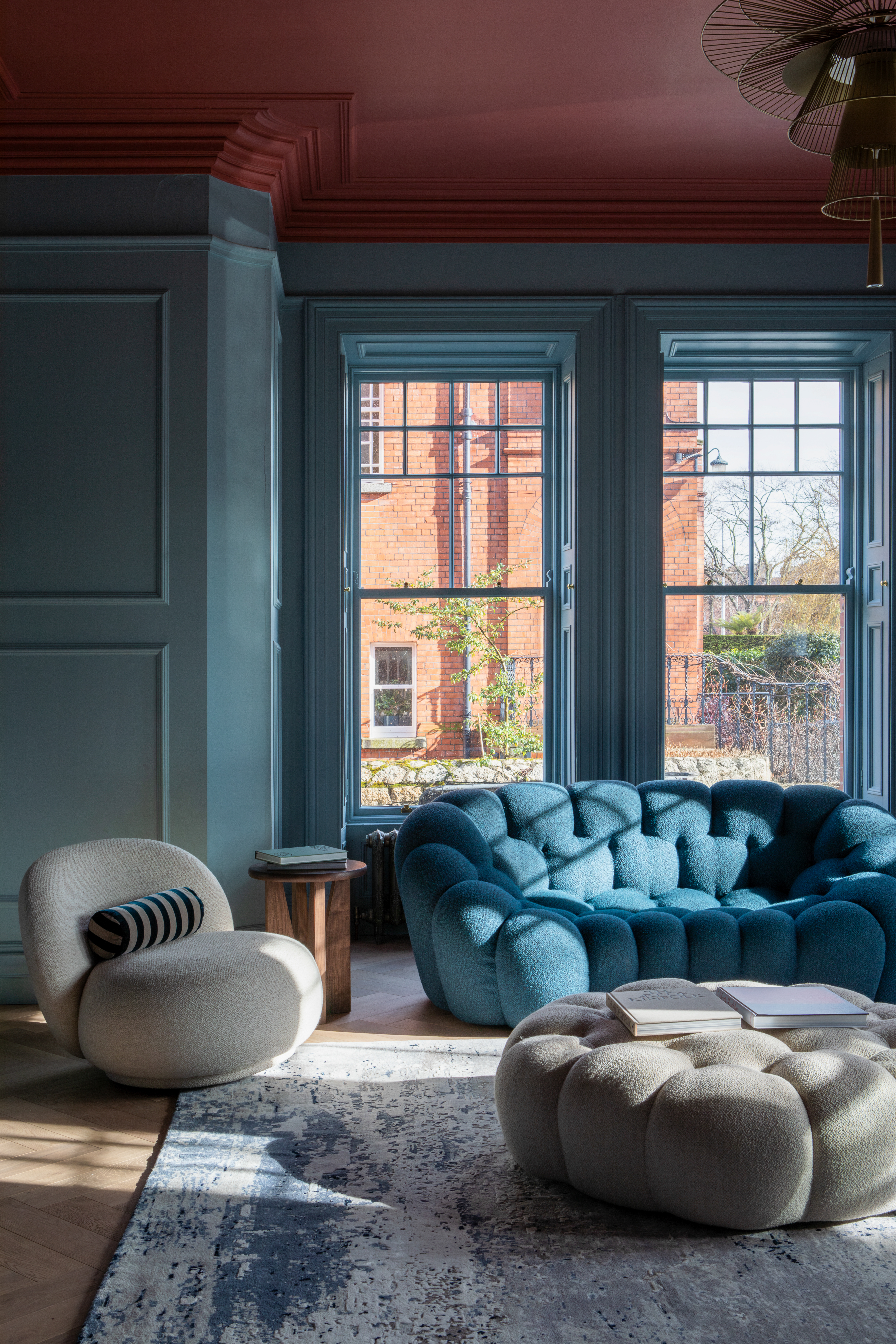 Living room with teal walls, blue sofa, and off-white armchair.
