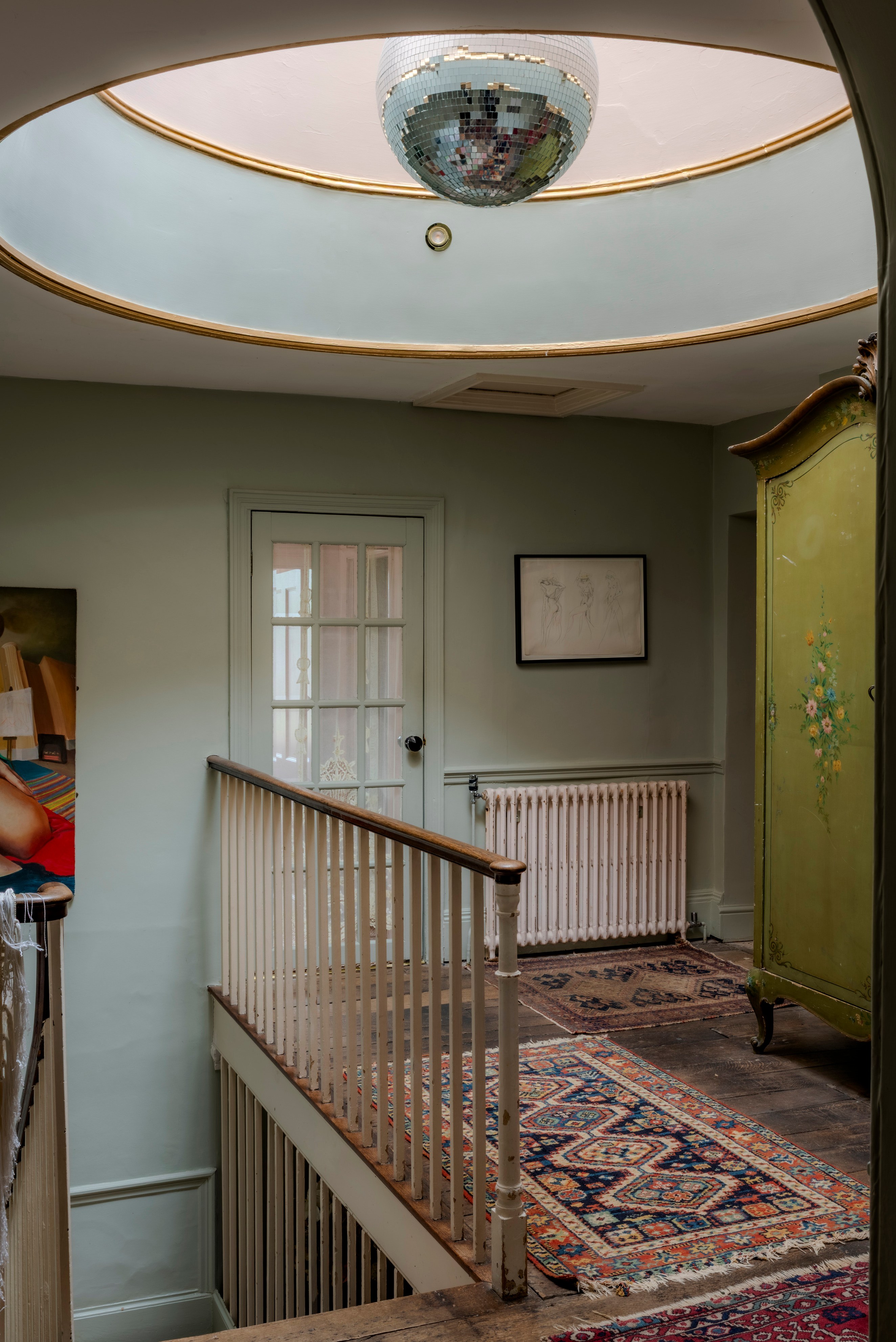 Hallway featuring a disco ball in a skylight, rugs, and an antique wardrobe.