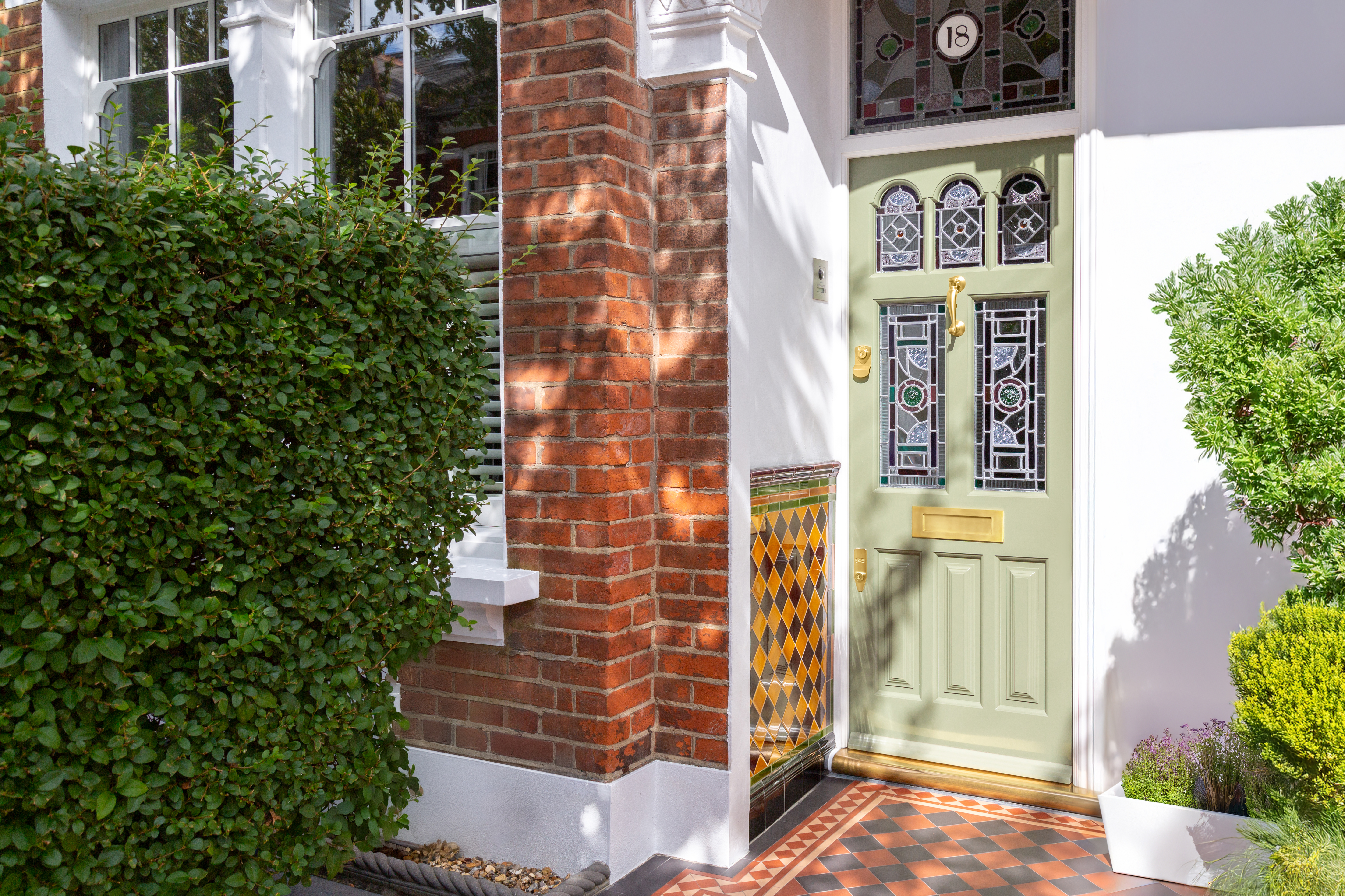 House entrance with sage green door and stained glass.