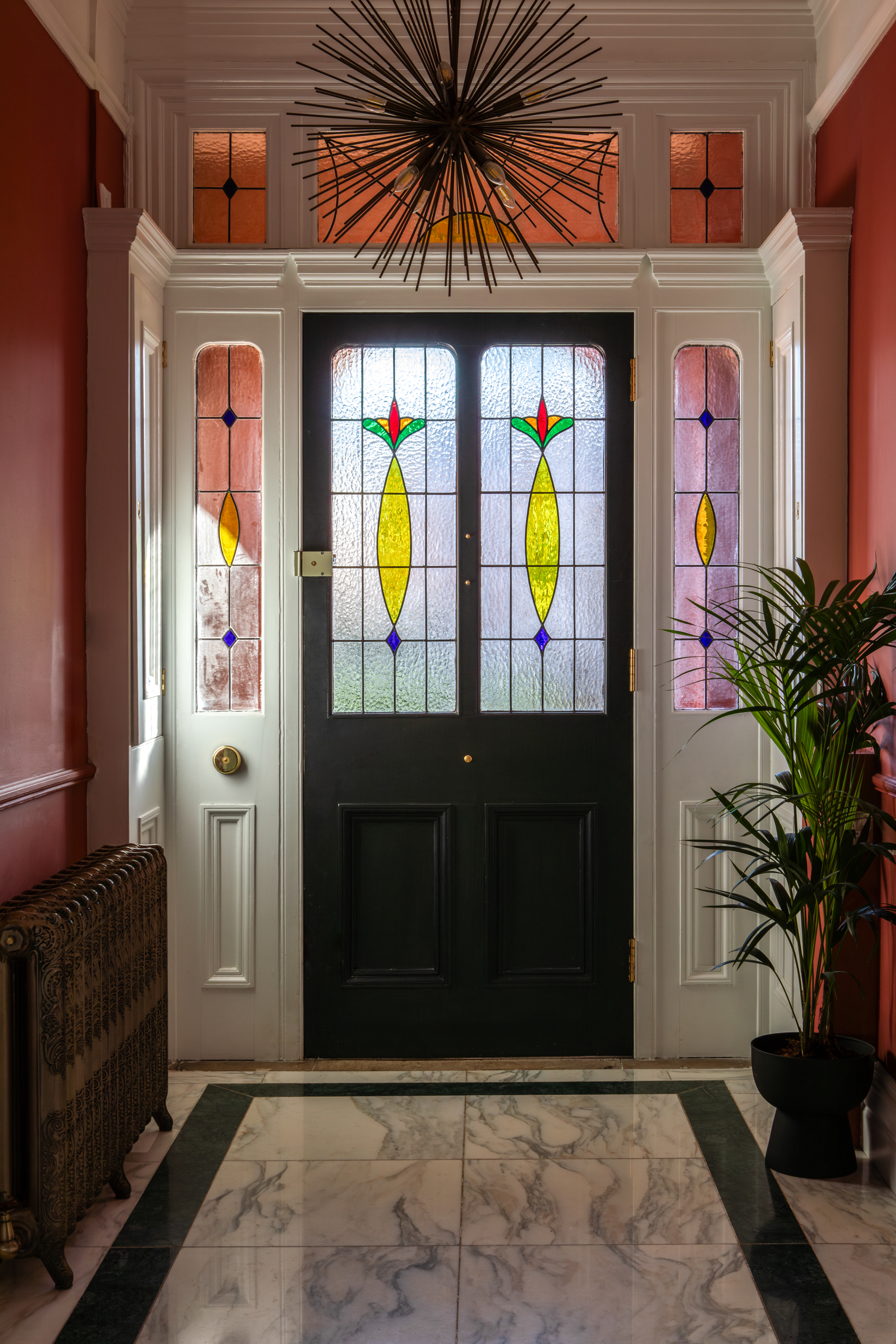 Interior view of a home's entrance with a black door featuring stained glass.
